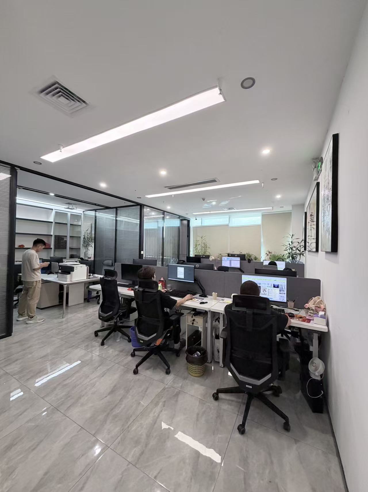 Office workspace with desks, computer monitors and glass-partitioned rooms