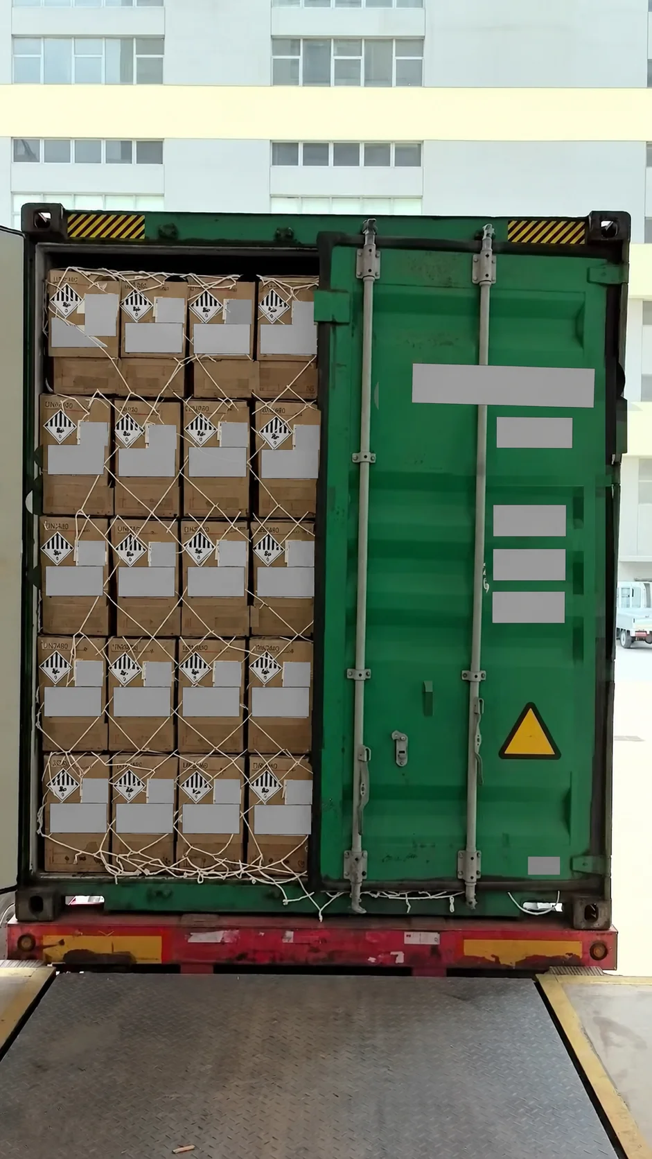 Privacy-edited container scene showing cartons and a securing net